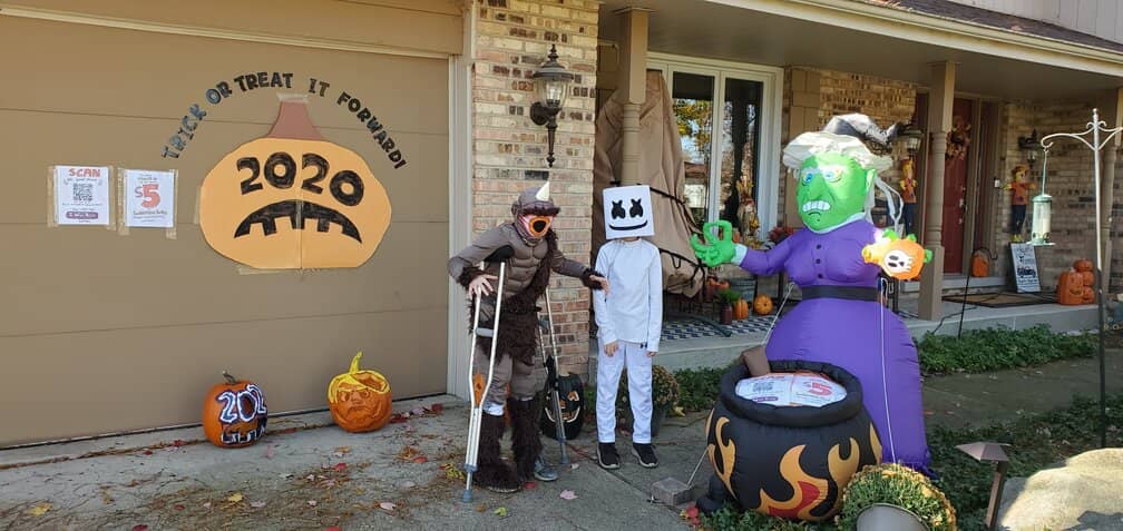 My kids posing in front of our house with signs for Trick or Treat It Forward
